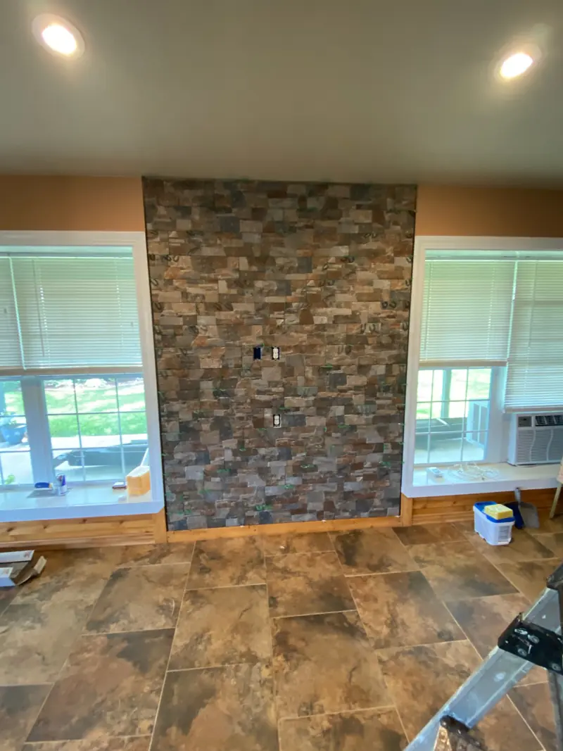 Stone accent wall between two windows over a tile floor.