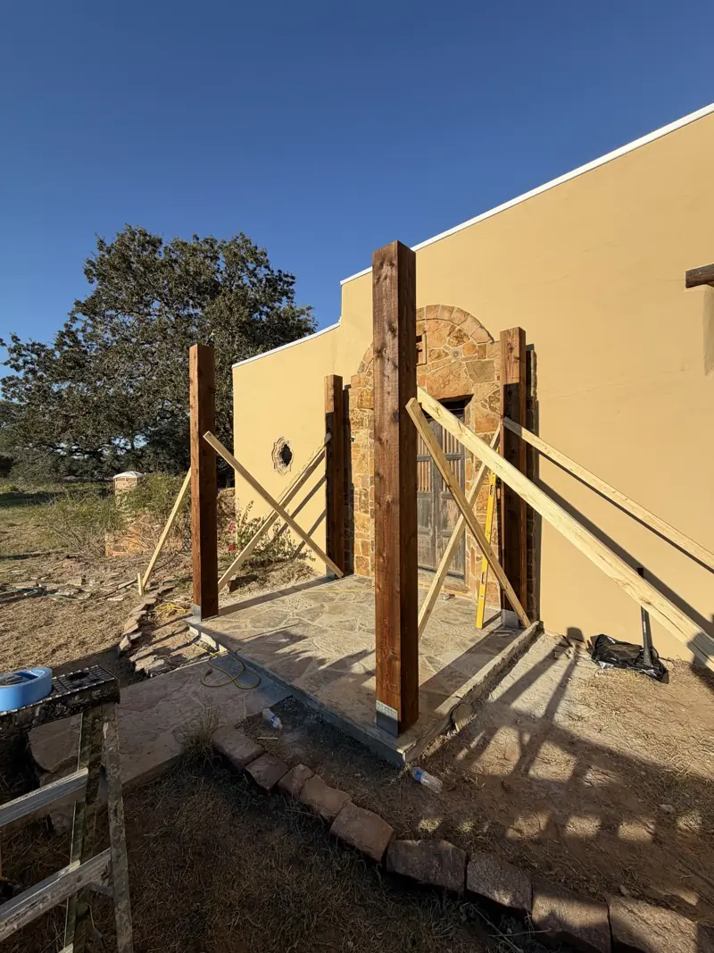 Four cedar posts standing on the flagstone porch, held plumb with wood braces.