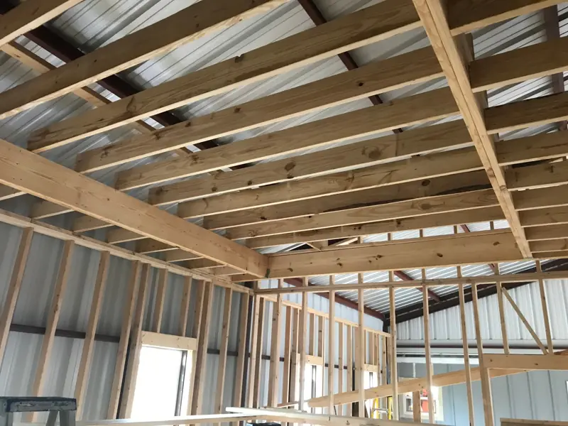 Wood ceiling joists and loft framing inside the steel building.