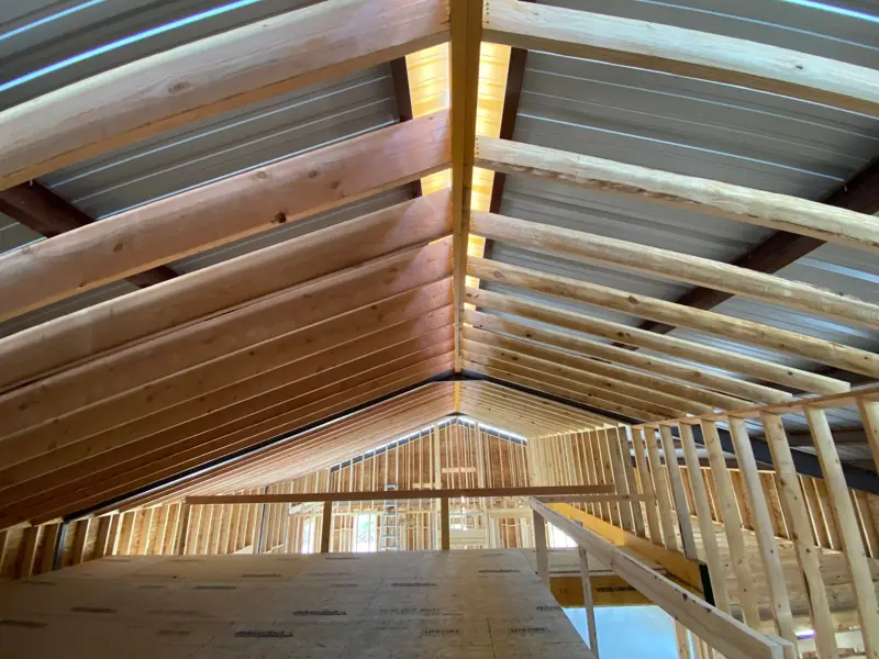 Wood rafters meeting at the ridge, with the loft railing below.
