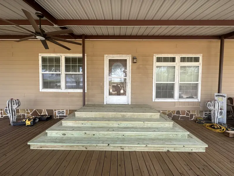 Finished wide wooden steps across a covered porch deck.