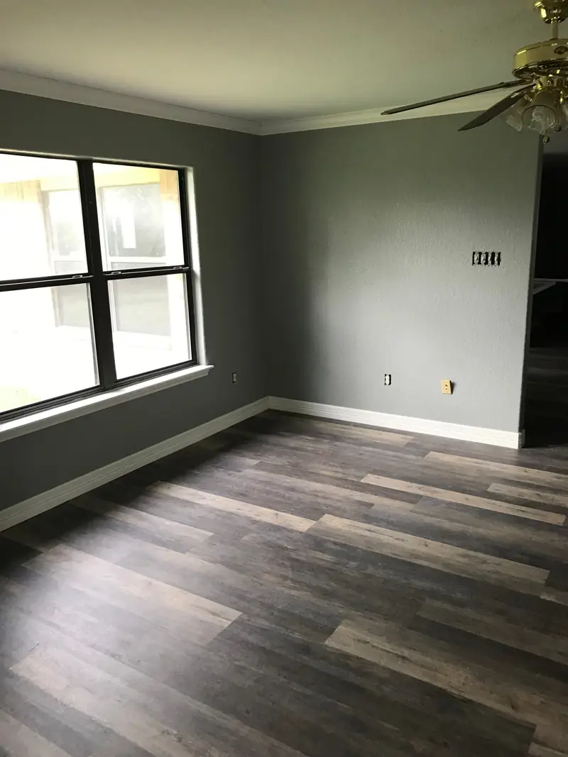 Bedroom with the new plank floor, gray walls and a ceiling fan.