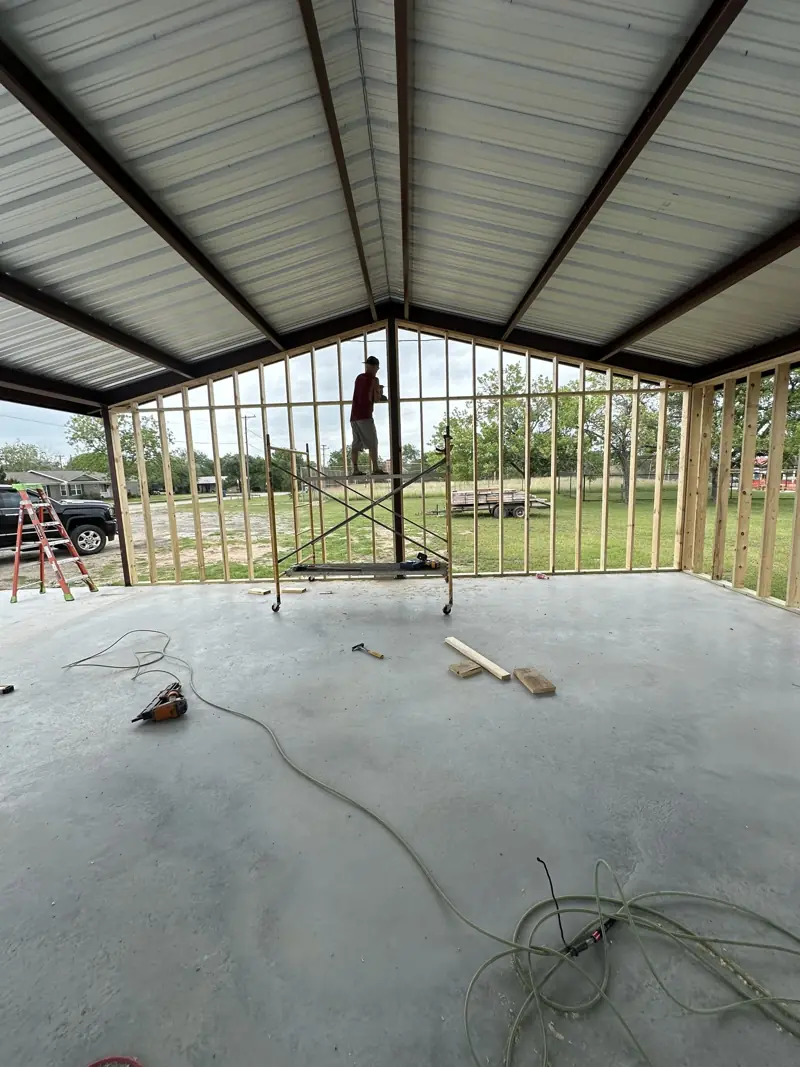 Wood stud walls framed under a steel frame metal roof on a concrete slab.