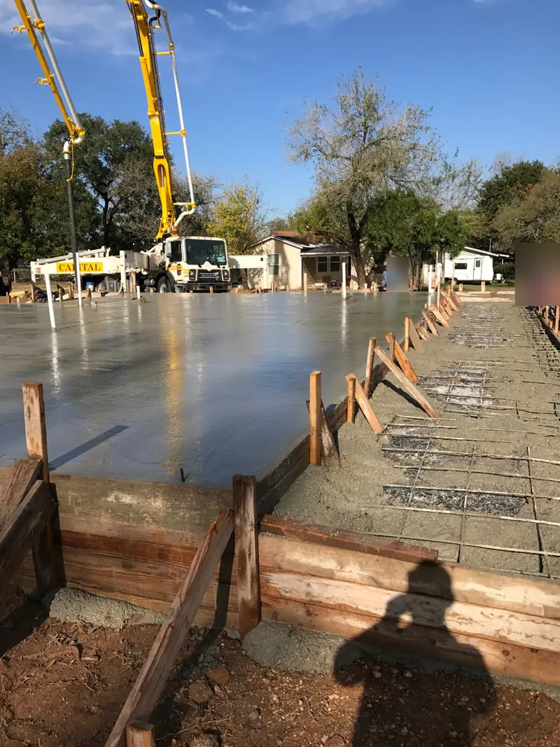 Fresh concrete in wood foundation forms, with a pump truck boom over the pour.