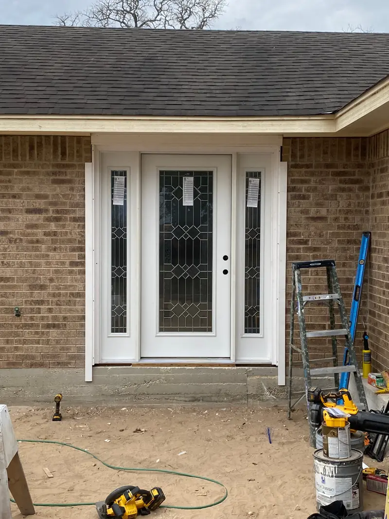 New front door with leaded-glass sidelights in the brick wall.