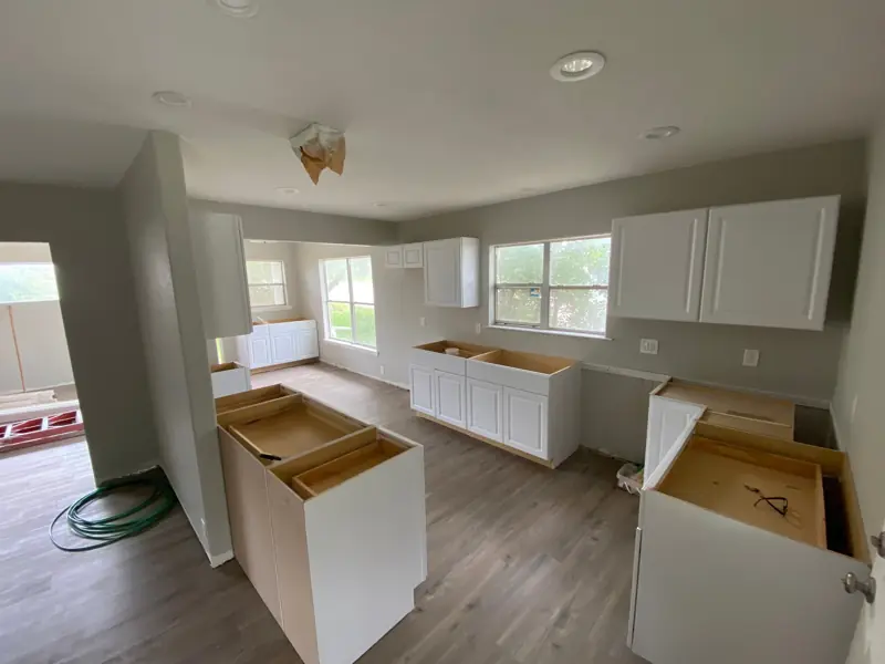 New white cabinets going in over a wood-look floor, gray paint on the walls.
