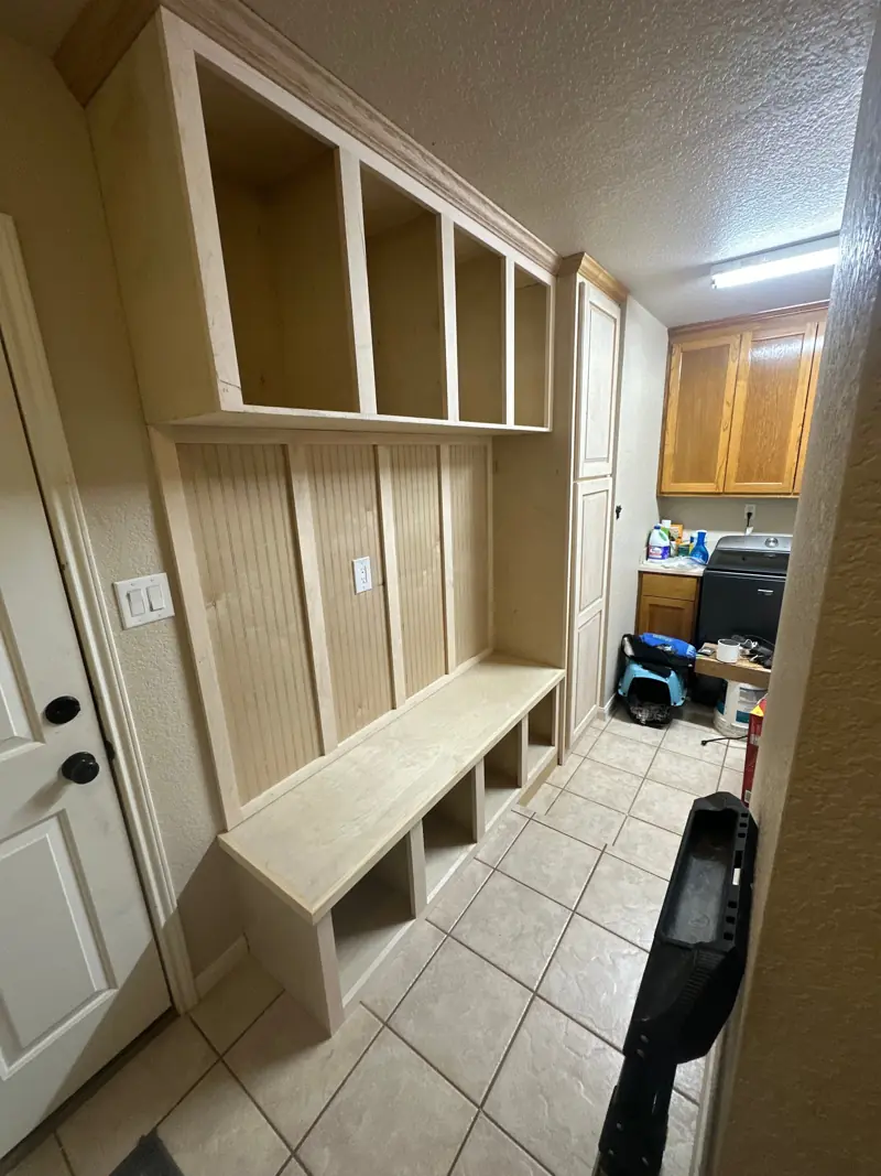 Built-in mudroom bench with beadboard locker backs and open cubbies above, before paint.