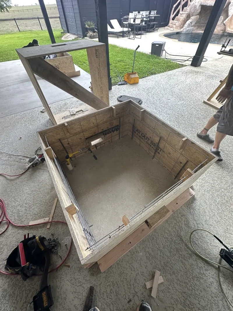 Wood box form with rebar and a gas pipe stub, built on the patio for the square concrete fire pit.