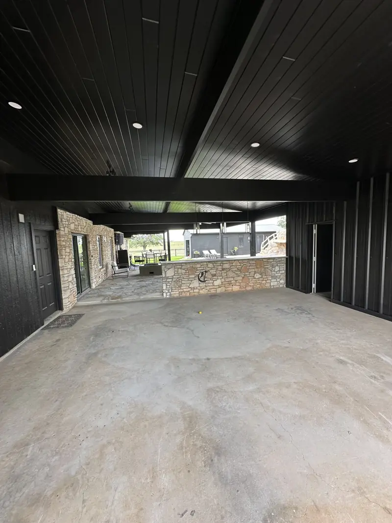 Breezeway under the new black plank ceiling with recessed lights, opening onto the flagstone patio and stone bar.