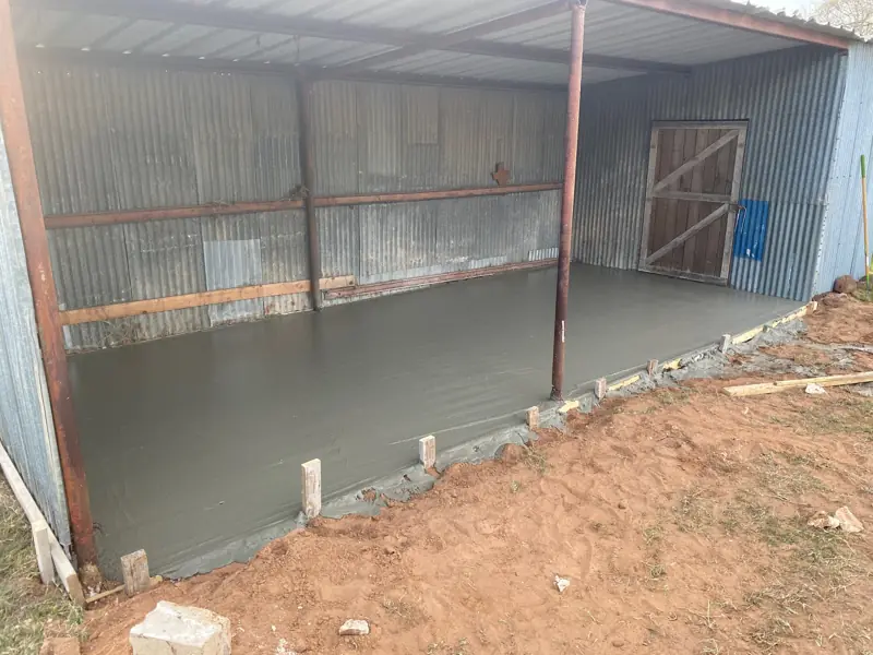 New concrete slab poured inside an open metal shed.