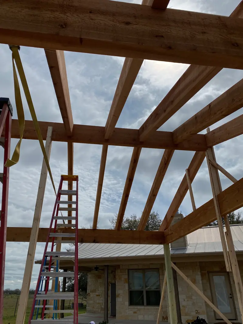 Cedar rafters from below, ladders standing on the slab.