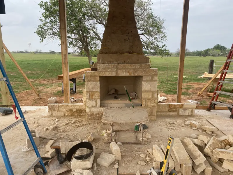 Stone fireplace front with the chimney above, stone scraps on the slab.
