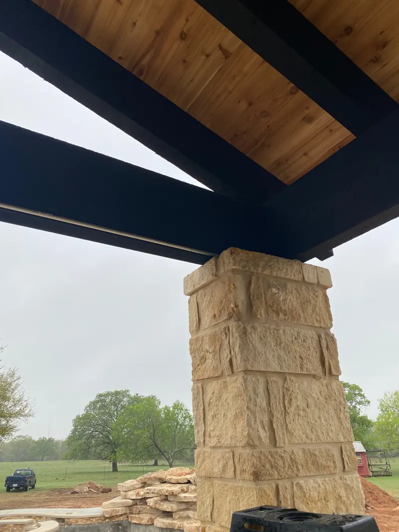 Stone column under a black beam and the cedar ceiling.