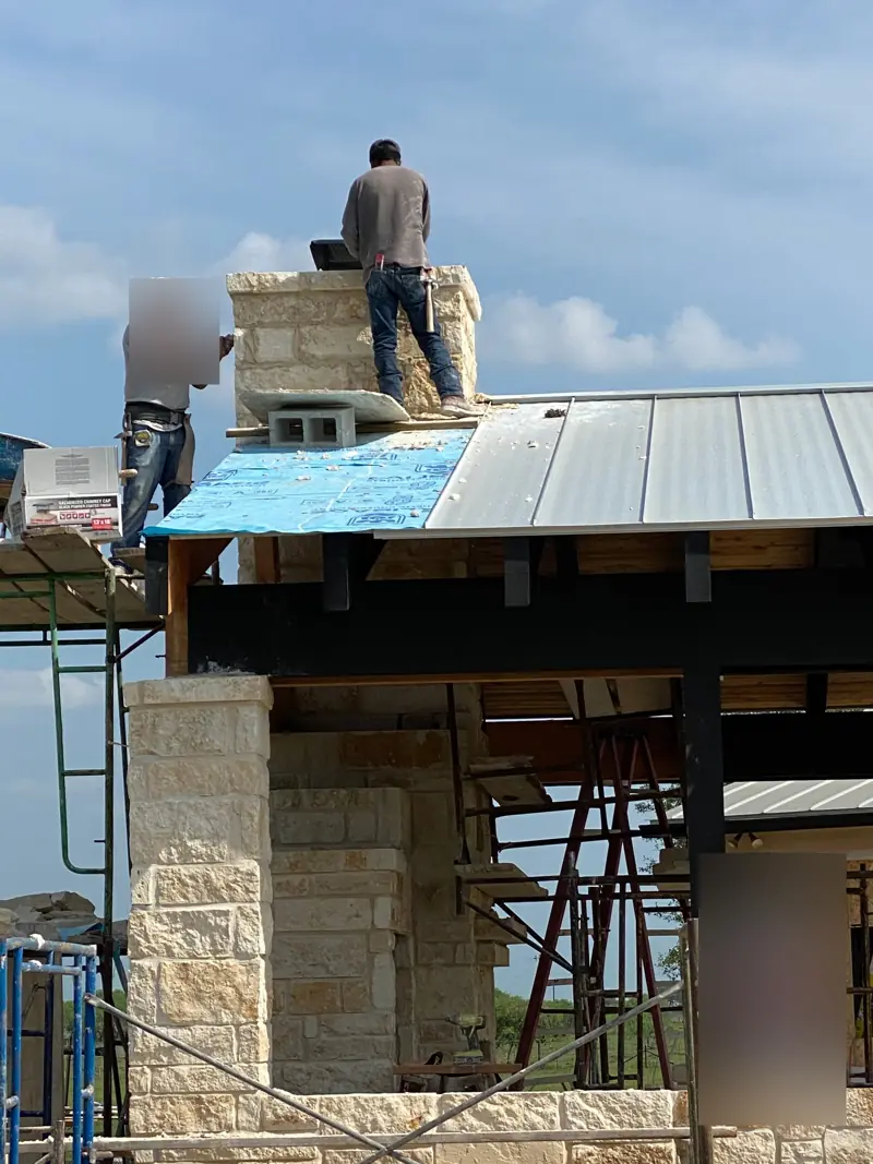 Masons on the roof building the top of the chimney.