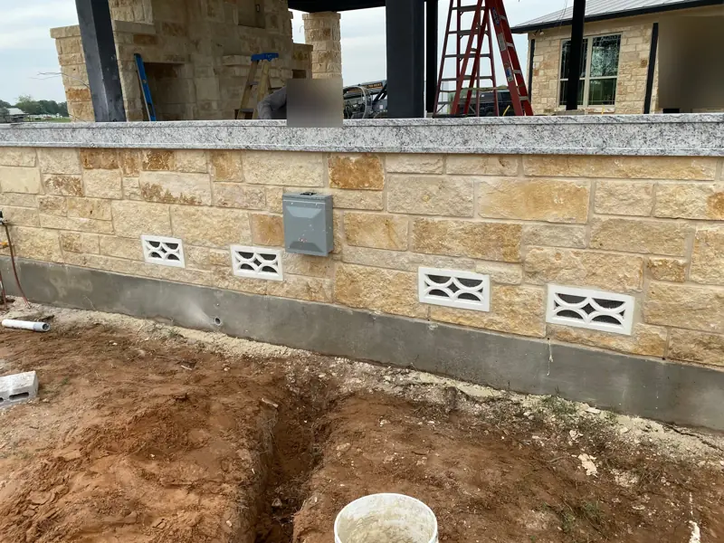 Stone kitchen counter with decorative vent blocks and a granite top.