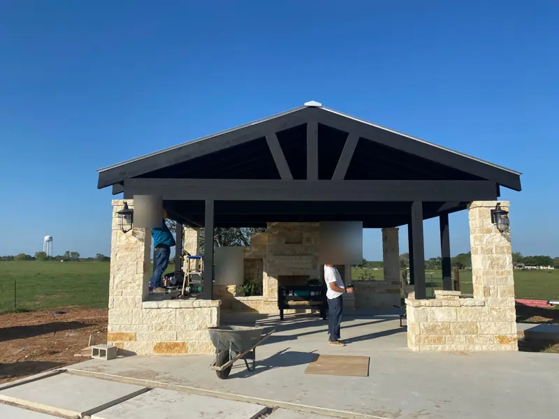 Finished pavilion with a black gable, stone columns and lanterns.