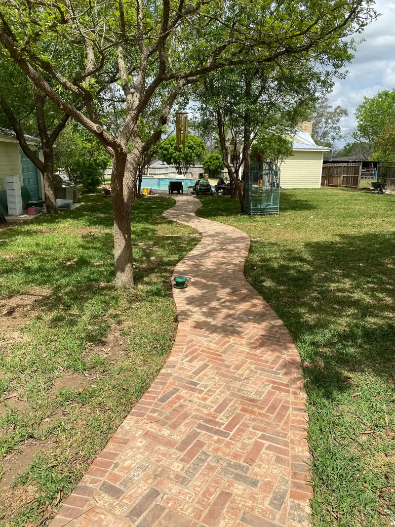 Herringbone brick walkway curving through the yard.