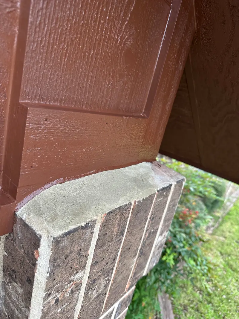 Painted beam end above a brick column cap.