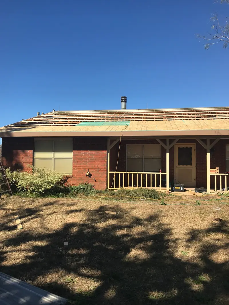 New roof decking along the front of the brick house, seen from the yard.