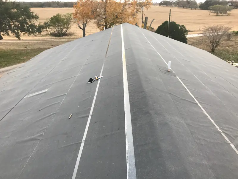 Gray synthetic underlayment over the roof ridge, looking along the roof line.