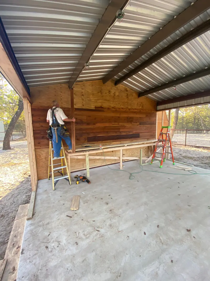 Reclaimed boards going up on the wall, a worker on a ladder.