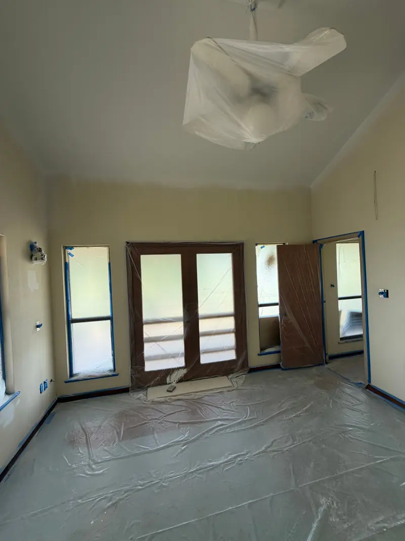 Room masked for paint, with plastic over the floor and French doors at the end.