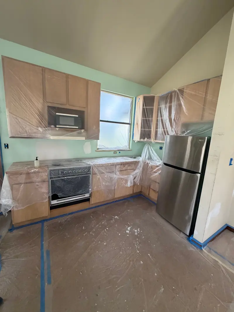 Kitchen masked for paint, the cabinets and counters covered.