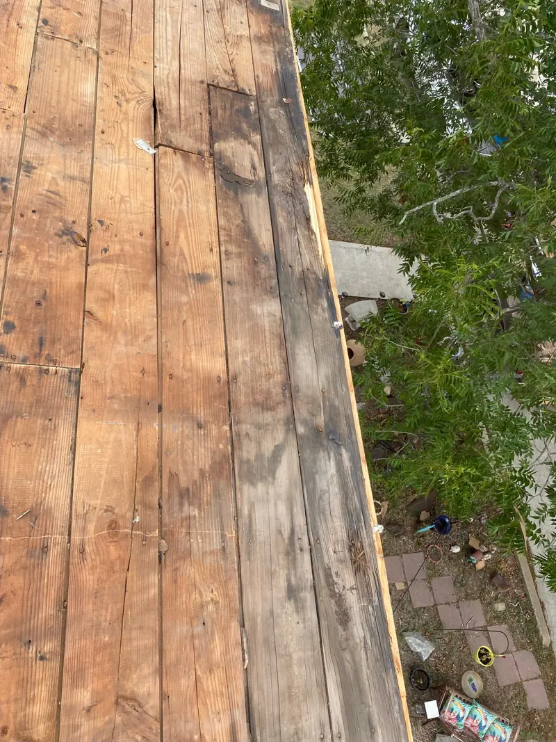 Old roof decking exposed, with rotten boards along the edge.