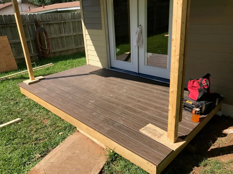 New composite deck at a pair of French doors, with wood posts at the corners.