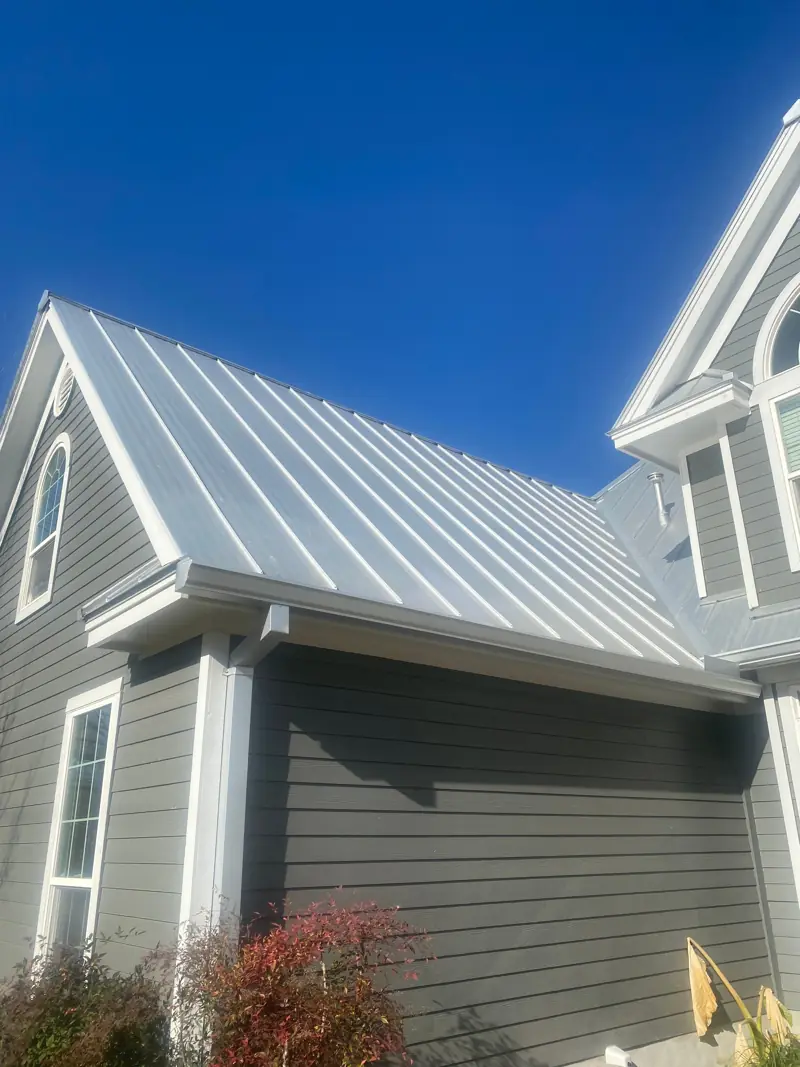 Standing seam metal roof on a gray two-story house.