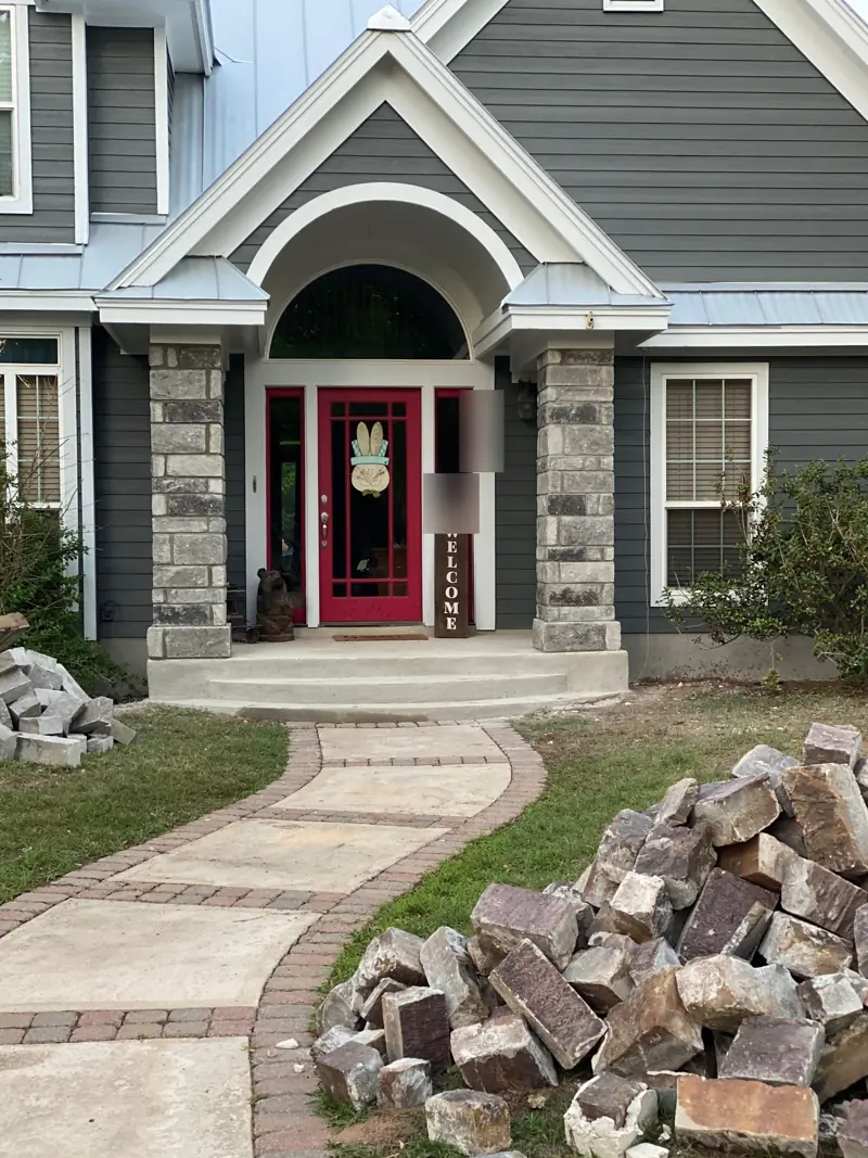 Entry with new gray stone columns on each side of a red front door.