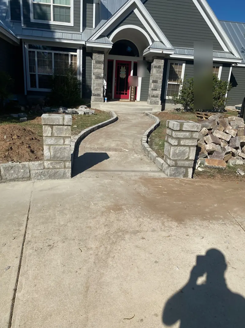 New stone pillars and curved low stone walls at the start of the front walk.