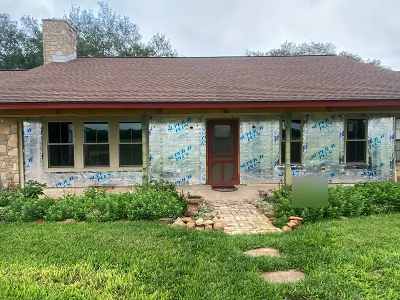 House with the old siding off and foil-faced foam board on the walls.